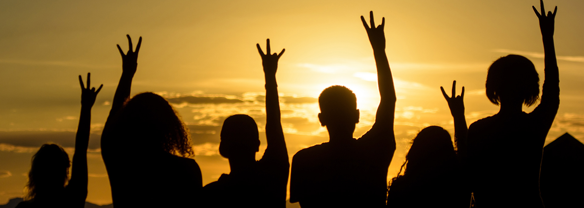 photo of students against the sunset making pitchfork hands
